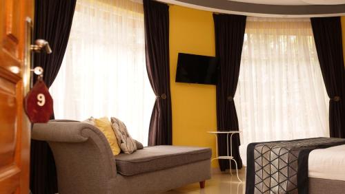 a bedroom with a chair and a bed and window at The Clarice House in Kisumu