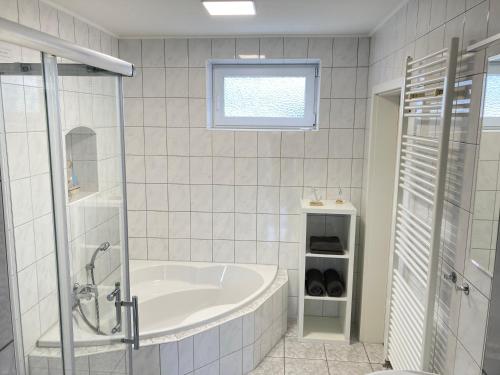 a white bathroom with a tub and a window at Ferienwohnung-Relax-Schleesen 