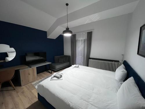 um quarto com uma grande cama branca e uma cadeira em LAKEVIEW Hotel & Apartments em Mavrovo