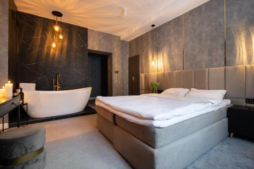a bedroom with a large bed and a bath tub at Apartamenty Drewno i Ogień in Olsztyn