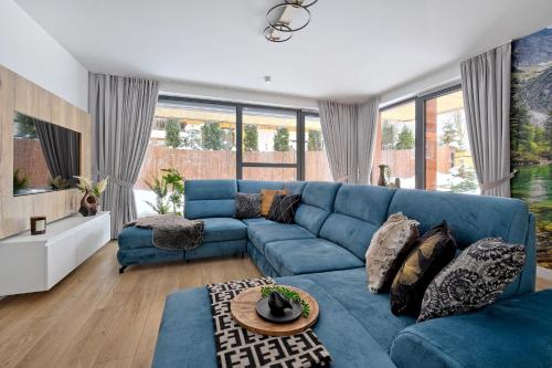 a blue couch in a living room with windows at Apartament Morskie Oko Odkryj Zakopane in Zakopane
