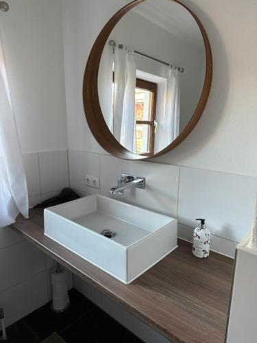 a bathroom with a white sink and a mirror at Apartmenthaus Der Johanneshof - tolle Lage nah am See in Schliersee