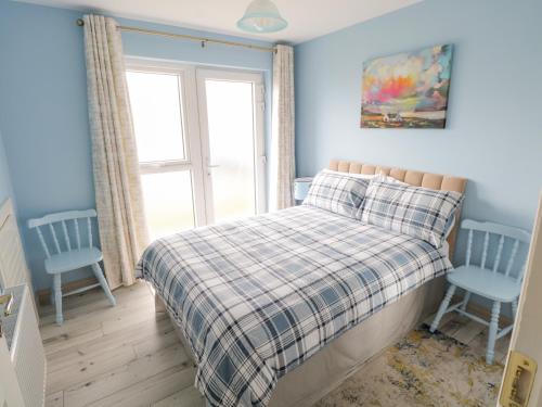 a bedroom with a bed and two blue chairs at 38 Carrowhubbock Holiday Village in Enniscrone