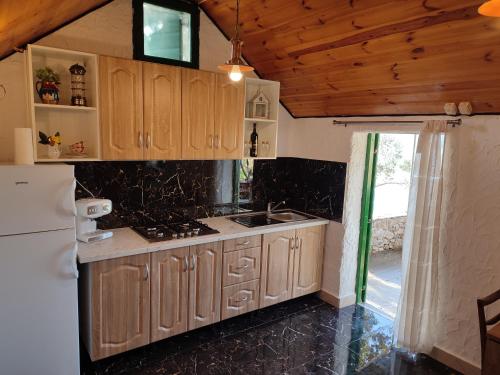 a kitchen with wooden cabinets and a white refrigerator at Robinson Galisnjak with amazing SEA VIEW & JACUZZI in Bol