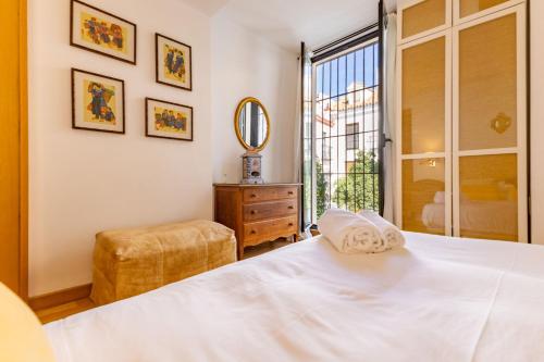 Schlafzimmer mit einem Bett, einem Spiegel und einem Fenster in der Unterkunft Alcazar Pool Villa by Valcambre in Sevilla