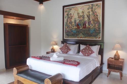 a bedroom with a bed with a large painting on the wall at Sebatu Tulen Villa in Tegalalang