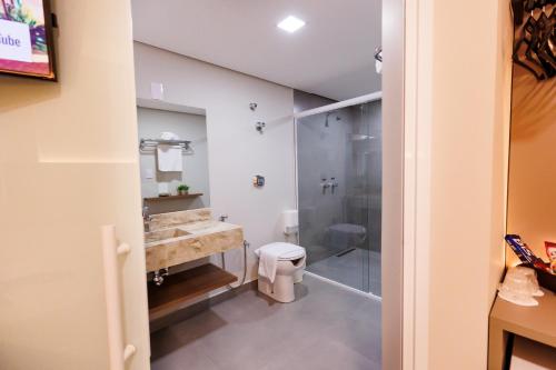 a bathroom with a shower and a sink and a toilet at Tonello Business Hotel in Campo Mourão