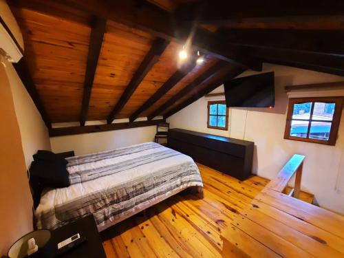 1 dormitorio con 1 cama en una habitación con suelo de madera en La Cabañita en Villa General Belgrano