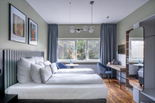 a bedroom with a white bed and a living room at numa I Bona Rooms & Apartments in Bonn
