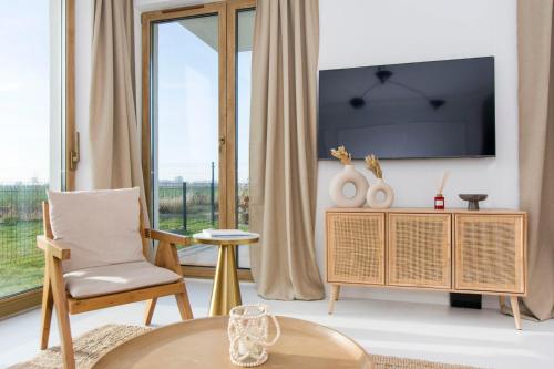 a living room with a tv and a chair and a table at Bursztynowe Tarasy - Apartamenty in Gdańsk