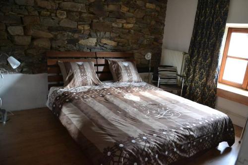 a bedroom with a large bed with a stone wall at La Campanelle te Odeigne Ardense vakantiewoning in Manhay