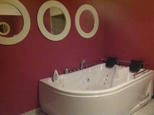 a bathroom with a tub and three mirrors on the wall at La Campanelle te Odeigne Ardense vakantiewoning in Manhay