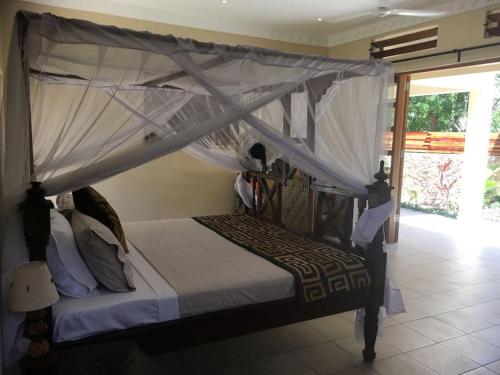 a bedroom with a bed with a canopy at C9 @ Diani Beachalets in Galu