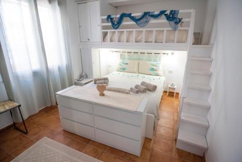 una camera per bambini con un letto bianco e un letto a castello di La Casa di Orimari a SantʼAntìoco