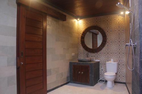 a bathroom with a toilet and a mirror at Sebatu Tulen Villa in Tegalalang
