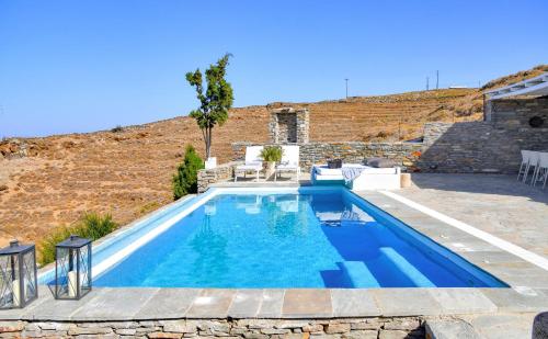 a swimming pool with blue water in a yard at Luxurious & Stylish villa with a swimming pool, sea and sunset view. in Ioulida
