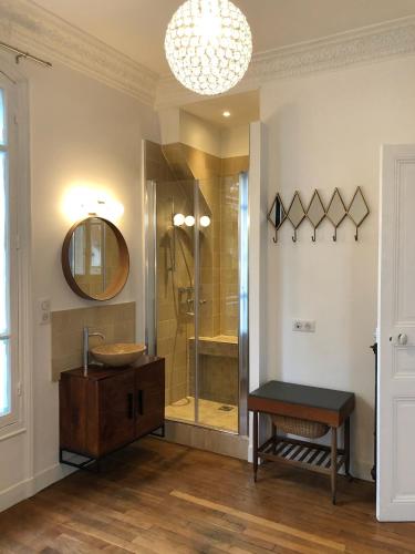 une salle de bain avec une douche, un lavabo et un miroir dans l'établissement Demeure début de siècle - Art & Détente & accès direct Paris, à Colombes
