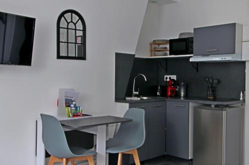 a kitchen with a table and two chairs and a counter at Location Tame in Douai