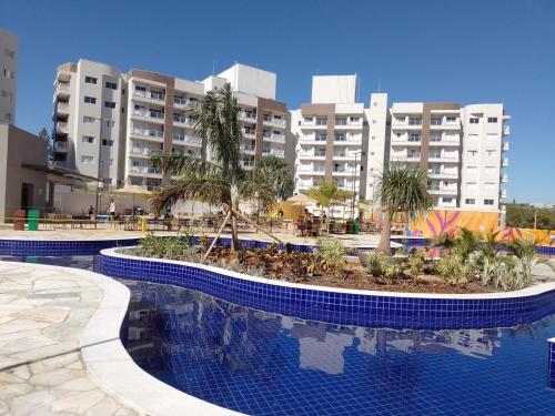 un complejo con piscina con palmeras y edificios en Apart Lagoaecotowers, en Caldas Novas