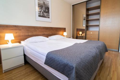 - une chambre avec un grand lit blanc et une tête de lit en bois dans l'établissement Warsaw Apartments - Apartamenty Wilanów, à Varsovie