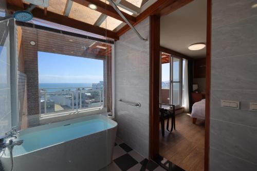 een badkamer met een bad en een groot raam bij Looksea in Hualien
