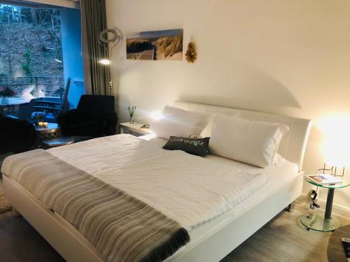 - une chambre avec un grand lit blanc et des oreillers blancs dans l'établissement Appartement Gluecks_Momente, à Glücksburg