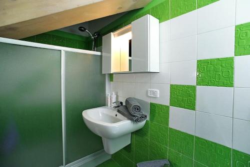 uma casa de banho verde e branca com um lavatório e um espelho em A un passo da Porta Nuova e dal centro: Io&Te em Turim