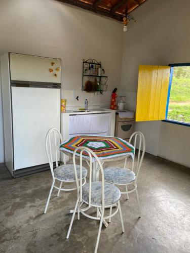 cocina con mesa, sillas y nevera en Chalé Boa Vista en Carrancas