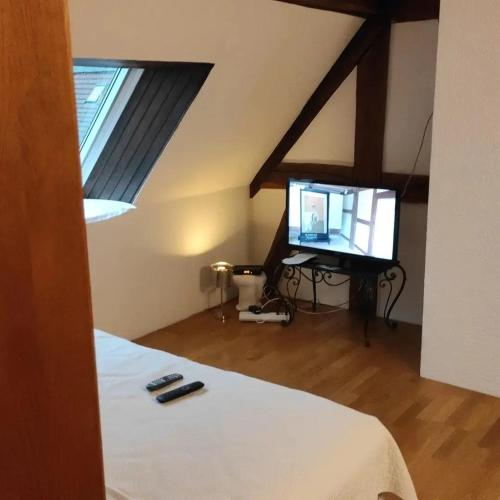 a bedroom with a bed and a television in a attic at GITE AU PETIT RUISSEAU-Etage et combles-maison alsacienne 4 personnes 4 nuitées minimum in Langensoultzbach