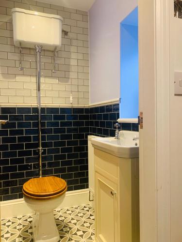 a bathroom with a wooden toilet and a sink at White Horses Anglesey in Newborough