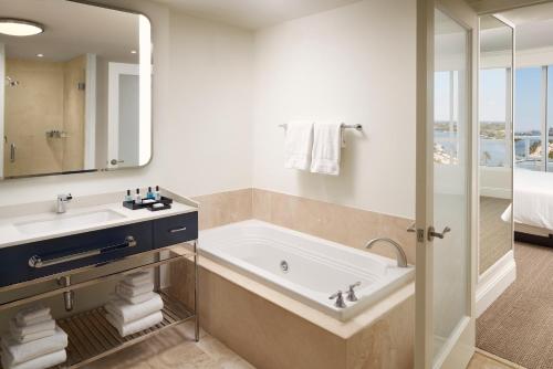 a bathroom with a tub and a sink and a mirror at Fontainebleau Miami Beach in Miami Beach