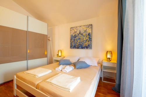 1 dormitorio con 1 cama con una pintura en la pared en Apartments Ela en Novalja