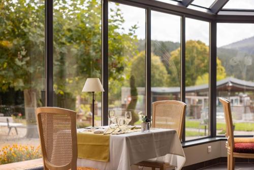 a table with a white table cloth and chairs and windows at Parc Hôtel in Wangenbourg
