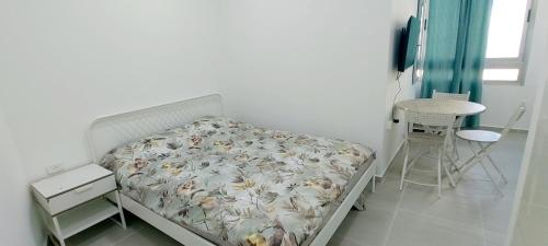 a bedroom with a bed and a table and a chair at 16 דירה מול הים ובריכה in Bat Yam