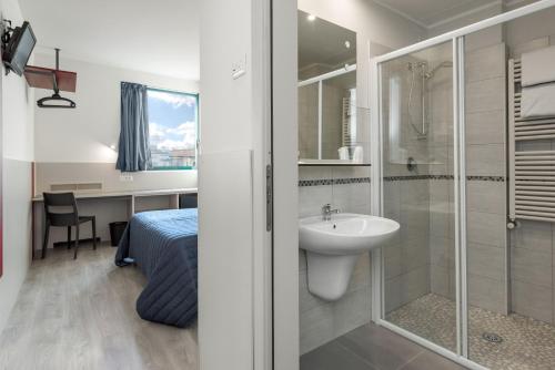 a bathroom with a shower and a sink and a bed at Hotel Porta Palio in Verona