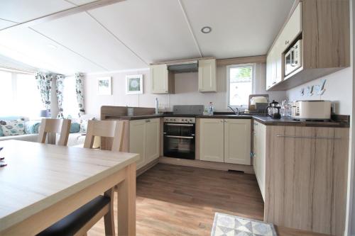 uma cozinha com armários brancos e uma mesa num quarto em 56 Seabreeze em Milford on Sea