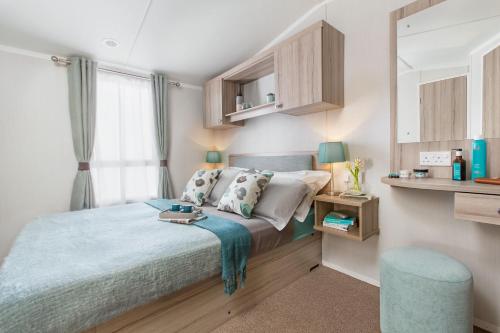 um pequeno quarto com uma cama e um banco azul em 56 Seabreeze em Milford on Sea
