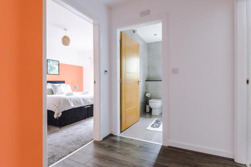 a bedroom with a bed and a door leading to a bathroom at Formby Village Apartments By Greenstay Serviced Accommodation - A Luxury 2 Bed Apt - Perfect for Couples, Friends, Families & Business Travellers - FREE Parking - Dog Friendly - Fast Wi-Fi - 6 in Formby