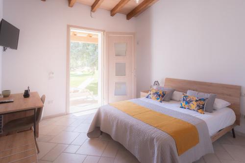 a bedroom with a bed and a desk and a window at Su Cappeddu Agriturismo in San Giorgio