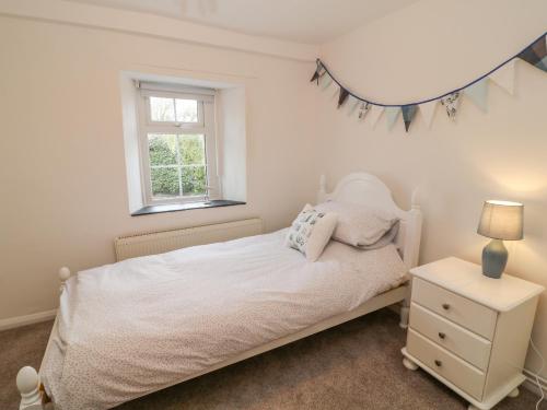 a bedroom with a white bed and a window at Bluebell in Week Saint Mary