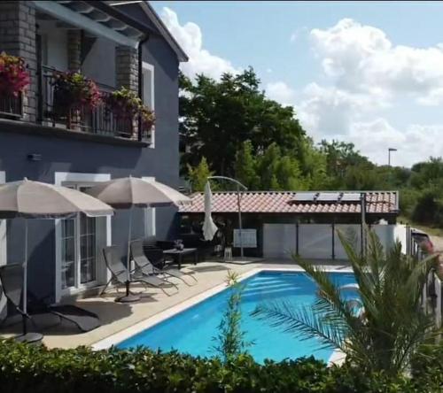 una piscina con sedie e ombrelloni accanto a una casa di LAVANDA house with apartments a Buje