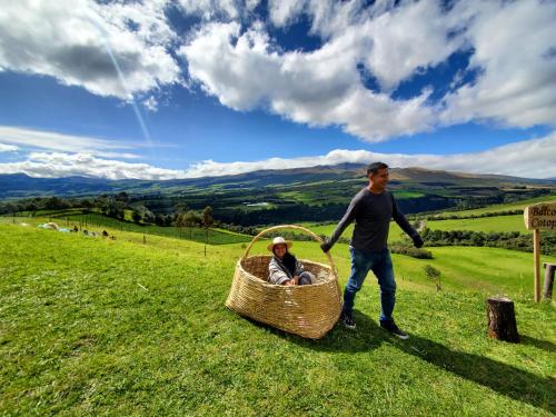 a man pushing a person in a basket on a hill at Balcon al Cotopaxi Hosteria in Sangolquí