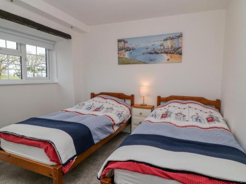 two beds in a bedroom with a painting on the wall at Foxglove in Week Saint Mary