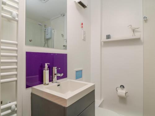 a bathroom with a sink and a purple wall at Foxglove in Week Saint Mary