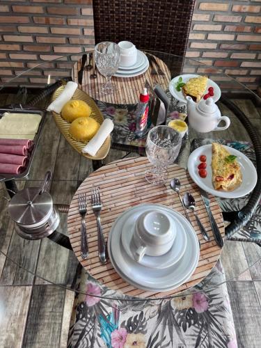 ein Tisch mit Tellern mit Essen und Besteck darauf in der Unterkunft Pousada BANGALÔS SOL DE LAGOINHA in Lagoinha