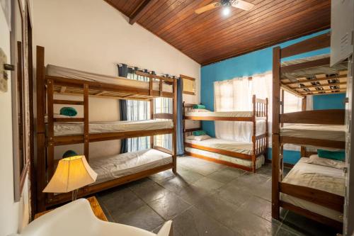 a room with three bunk beds and a lamp at Hostel Papagaio in Abraão
