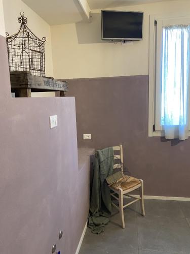 a room with a chair and a tv on a wall at B&B MELLONI STREET in Dolo
