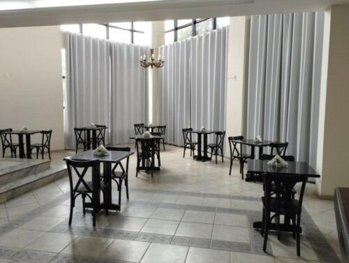 una sala da pranzo con tavoli, sedie e tende di Summit Inn Hotel Pouso Alegre a Pouso Alegre