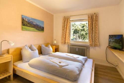 Schlafzimmer mit einem Bett, einem Fenster und einem TV in der Unterkunft Malerblick - a73966 in Mittenwald