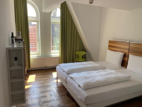 een slaapkamer met 2 bedden en een groen gordijn bij HOPPER Hotel St. Josef in Keulen